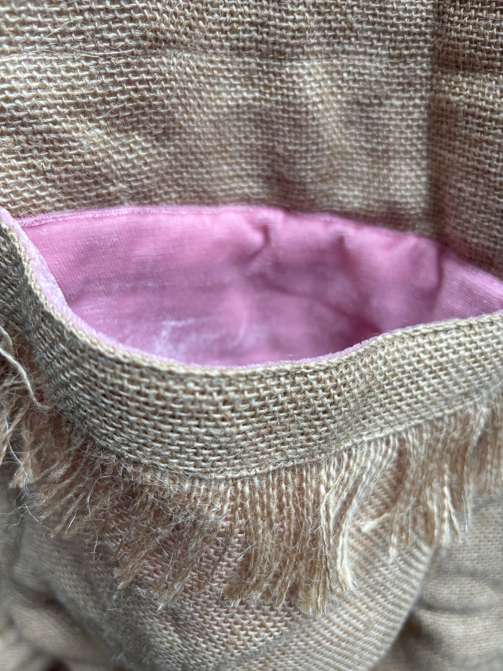 Close-up of a fabric basket with a pink interior and burlap exterior.