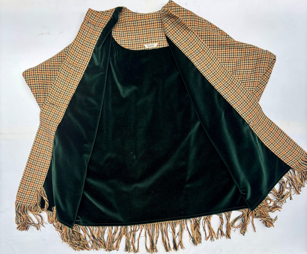 Green velvet garment with plaid trim and fringes on a white background