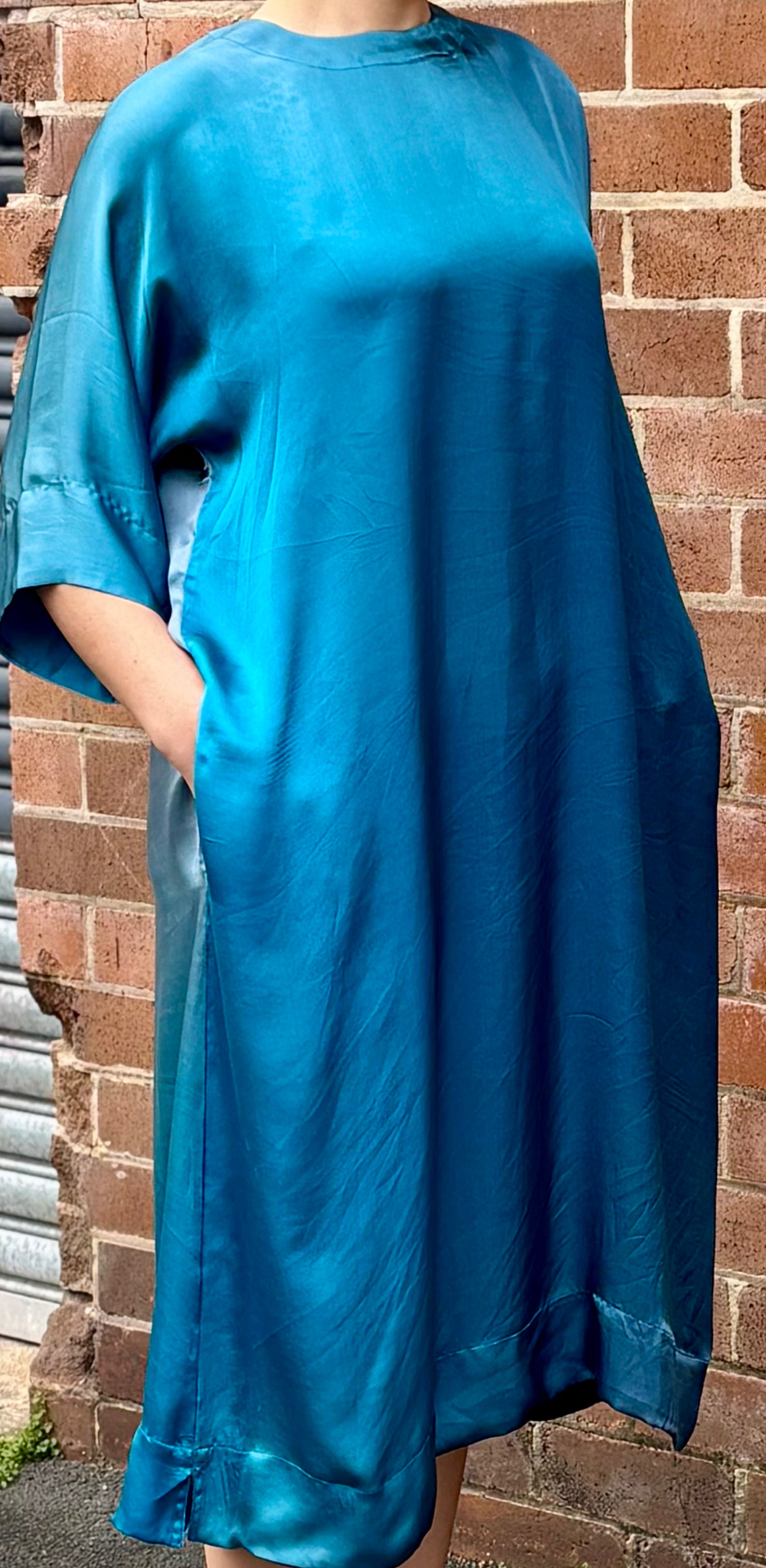 Person wearing a blue dress against a brick wall.